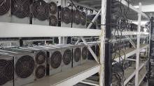 A mining farm in Sichuan showcasing numerous mining rigs under sweeping green landscapes.
